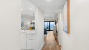 Une cuisine moderne avec des meubles blancs, un plancher en bois et une vue sur l’extérieur.
