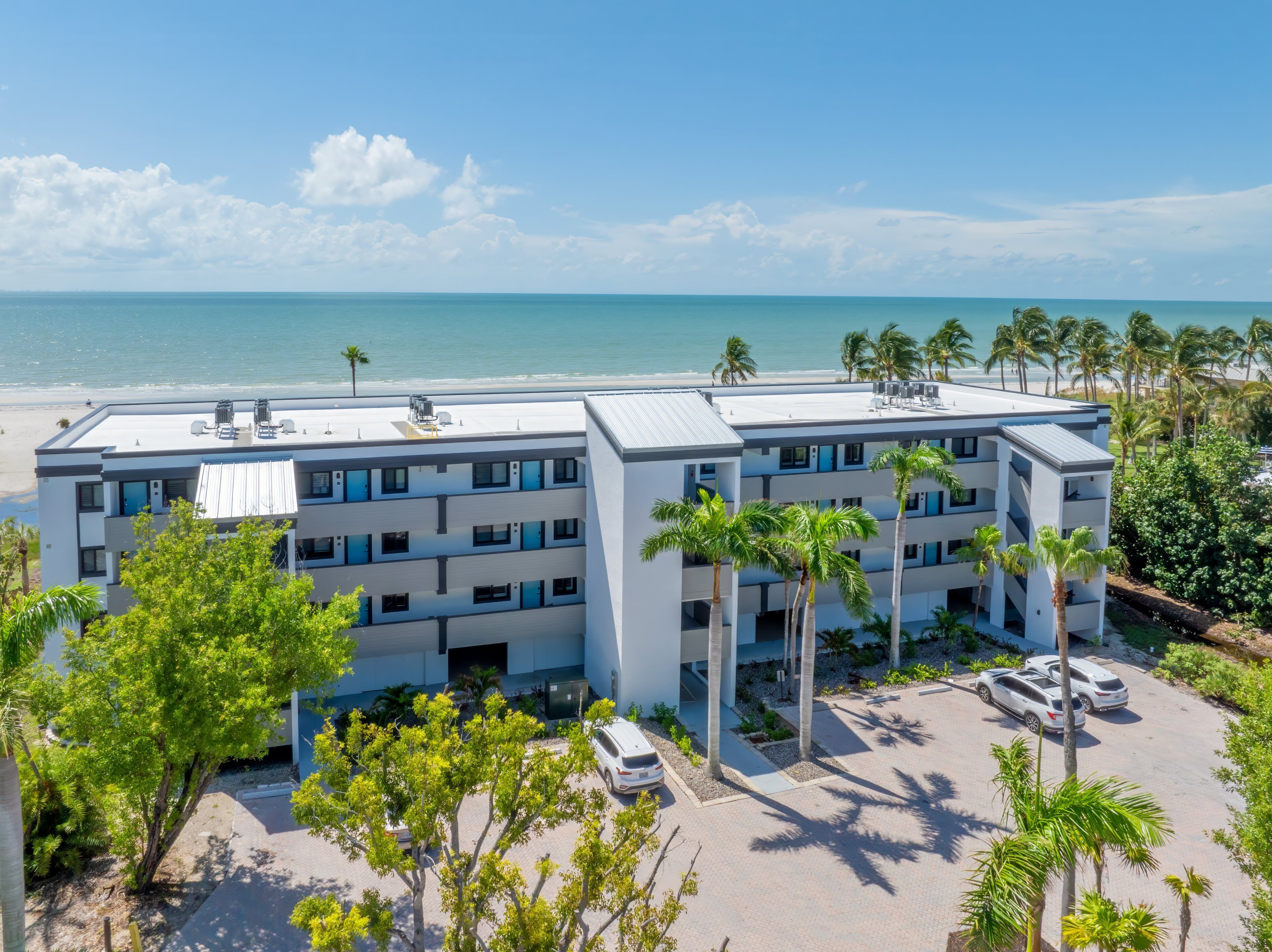 A modern hotel with a flat roof, multiple balconies, and a view of the beach and ocean.