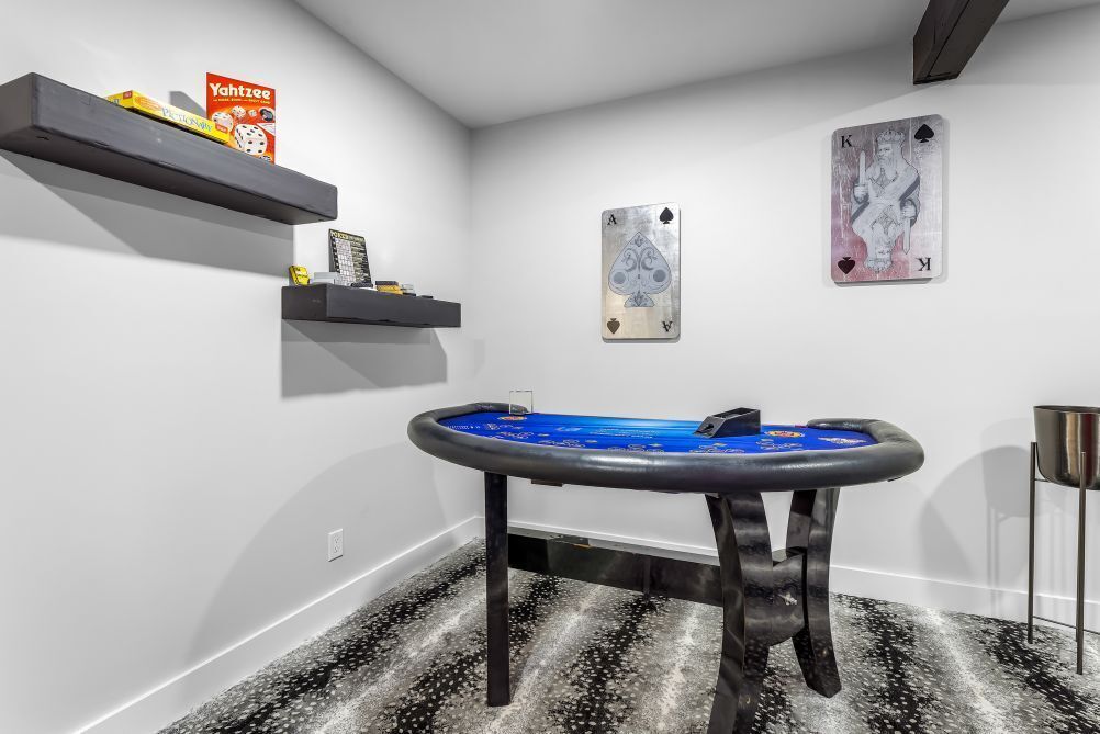 A room with a pool table, two playing cards on the wall, and a Yahtzee box on a shelf.