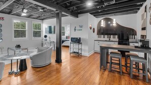 A modern kitchen with a large island, a dining area with a round table and bar stools, and a living space with a sofa and coffee table. - Elegant 1BR Condo at The Sanctuary Near Local Attractions (Biloxi)