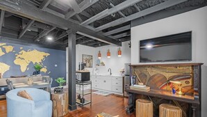 A modern living room with a large world map on the wall, a round coffee table, and a television. - The Sanctuary Spacious 1BR Condo. Stay in Comfort! (Biloxi)