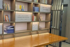 Una estantería de madera con libros y una cesta de metal.