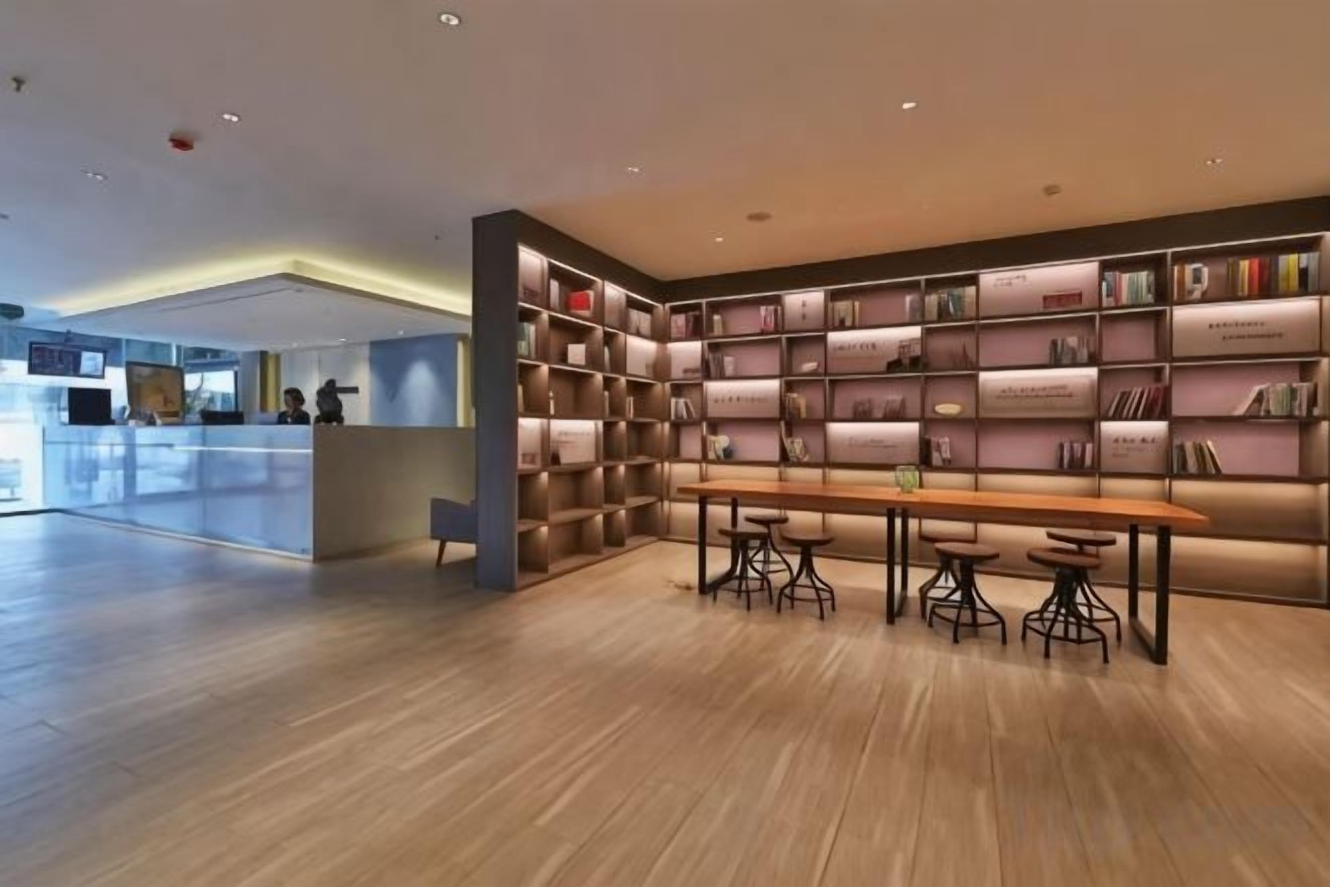 A modern library with bookshelves, a wooden table, and chairs.