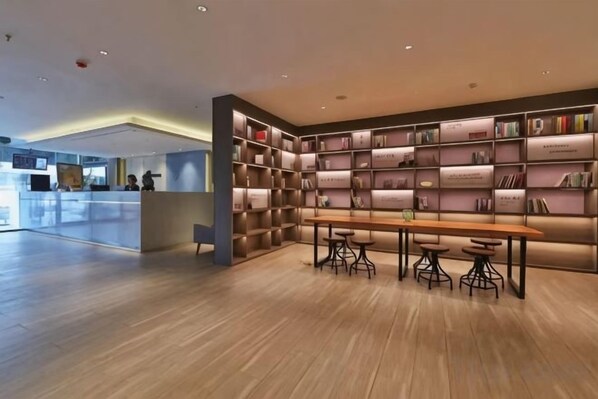A modern library with bookshelves, a wooden table, and chairs. - Homeinn Hotel (Qingdao Zhengyang Middle Road Wanda Plaza) (Qingdao)