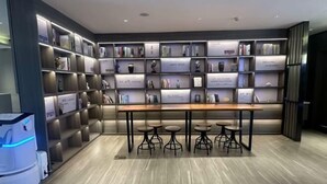A modern library with bookshelves, a wooden table, and bar stools. - Homeinn Hotel (Qingdao Zhengyang Middle Road Wanda Plaza) (Qingdao)