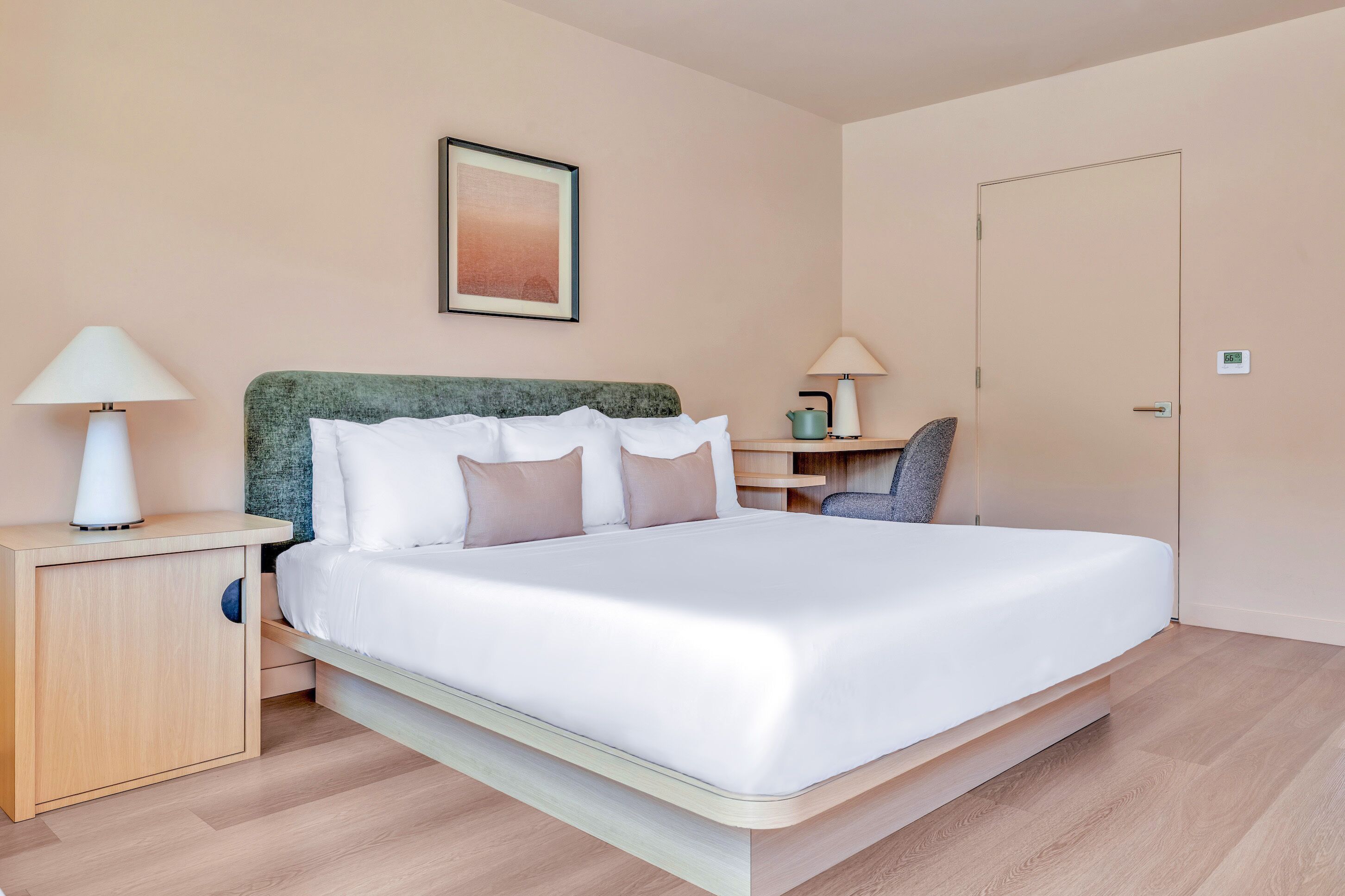 Un dormitorio moderno con cama, mesitas de noche, lámpara, silla y una puerta.