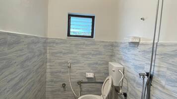 A small bathroom with a toilet, a window, and a shower.