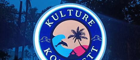 A sign with the words "KULTURE KONNECT" and a graphic of a palm tree, waves, and a sunset.