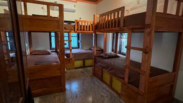 Una habitación con literas, techo de madera y pared decorada.
