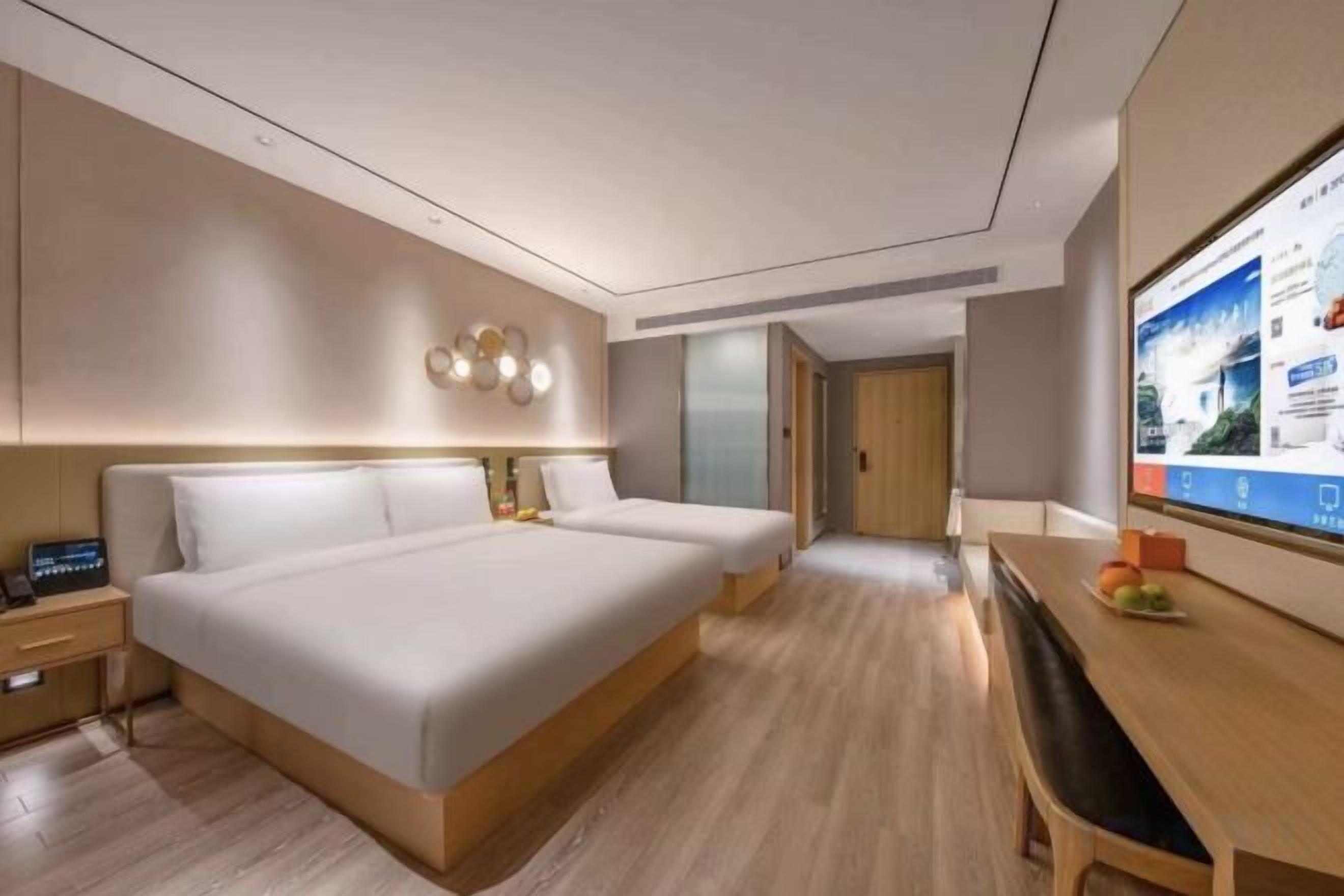 A modern hotel room with a large bed, bedside tables, a desk, and a television.