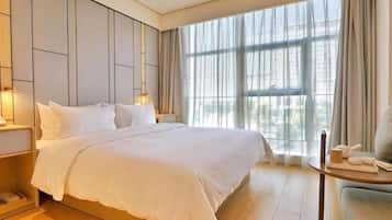 Una habitación de hotel con una cama grande, mesitas de noche, una silla y vistas a través de una ventana.
