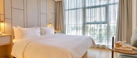 A hotel room with a large bed, bedside tables, a chair, and a view through a window.
