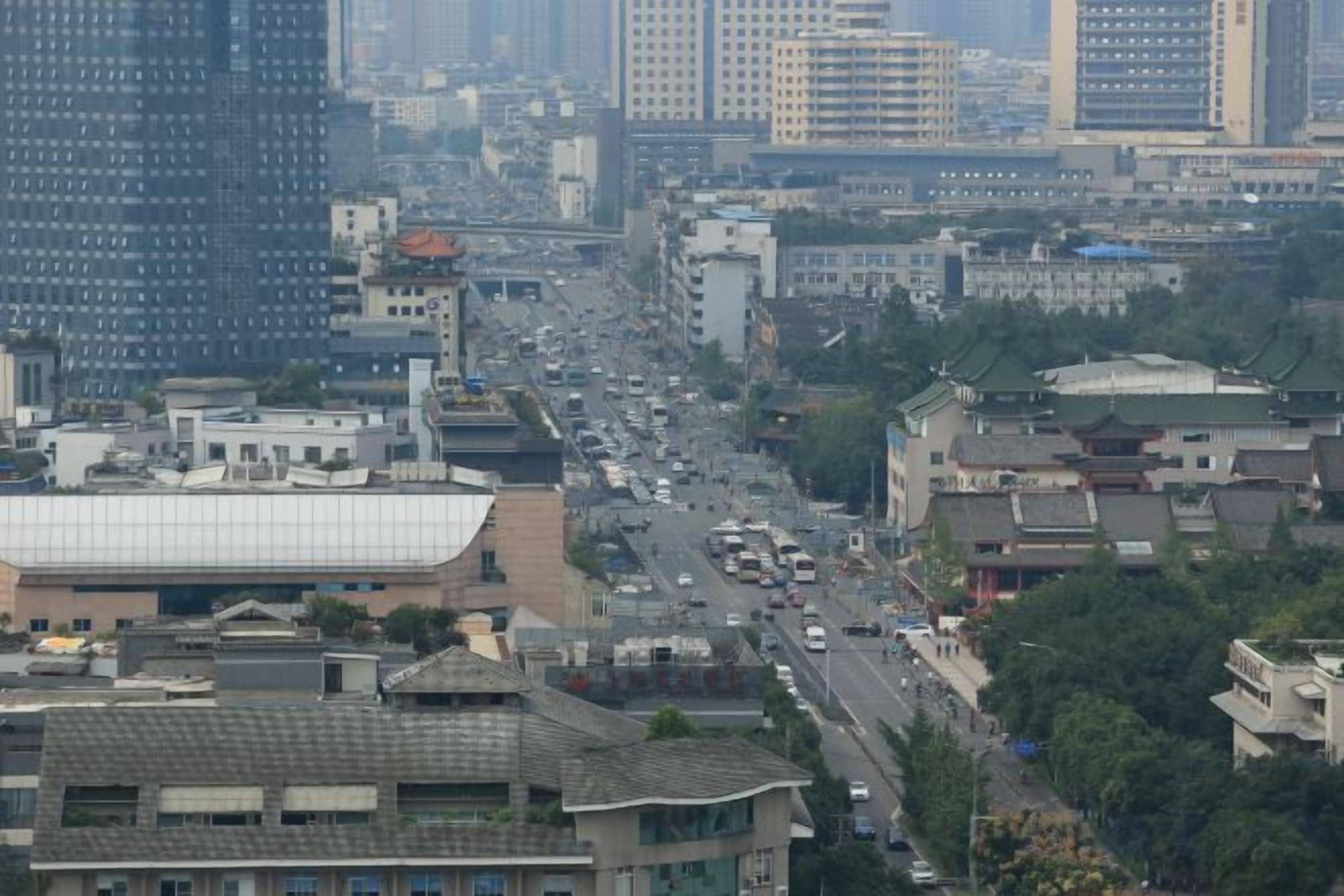 A cityscape with tall buildings, a busy street, and a mix of modern and traditional architecture.