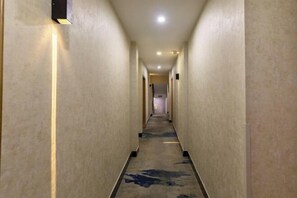 En lång, smal hall med beige väggar och en mönstrad matta.