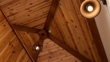 Un plafond en bois avec un luminaire suspendu et une structure de poutres apparentes.