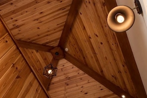 Eine Holzbalkendecke mit einer hängenden Leuchte und sichtbarer Trägerstruktur.