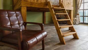 A room with a wooden ladder, a leather chair, and a bunk bed against a green wall.