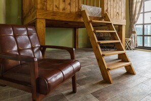 A room with a wooden ladder, a leather chair, and a bunk bed against a green wall. - Forest Bed and Breakfast(Pet friendly) (Hualien)