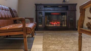 A living room with a fireplace, a sofa, and a rug.