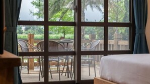 A room with a large window, a bed, and a view of outdoor furniture. - Forest Bed and Breakfast(Pet friendly) (Hualien)