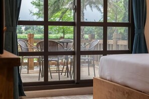 Una habitació amb una finestra gran, un llit i vistes a mobiliari exterior.
