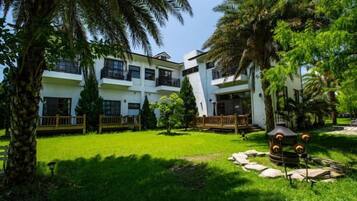 A hotel with multiple floors, outdoor seating, and lush greenery.