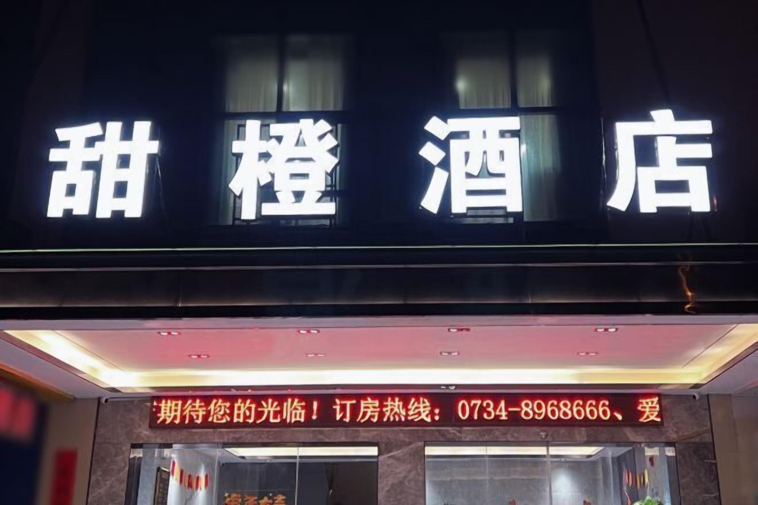 Un letrero de hotel con caracteres chinos y un número de contacto para reservas.