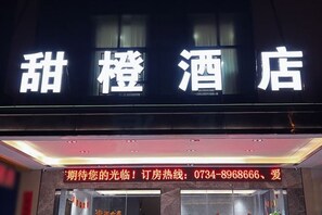 Un letrero de hotel con caracteres chinos y un número de contacto para reservas.