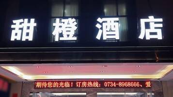 A hotel sign with the name 'Sweet Orange Hotel' and a contact number for inquiries.