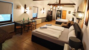 A cozy, well-lit room with a bed, a desk, and a dining area.