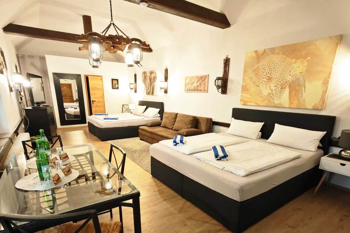A modern bedroom with a large bed, a desk, and a dining area.