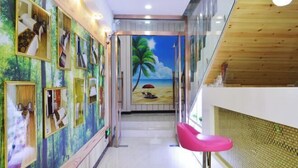 A hallway with a wooden ceiling, a pink chair, and a mural of a beach scene. - Shijiazhuang Yiyou Express Hotel (Youyi South Street Hebei Province Letters and Calls Bureau Branch) (Shijiazhuang)