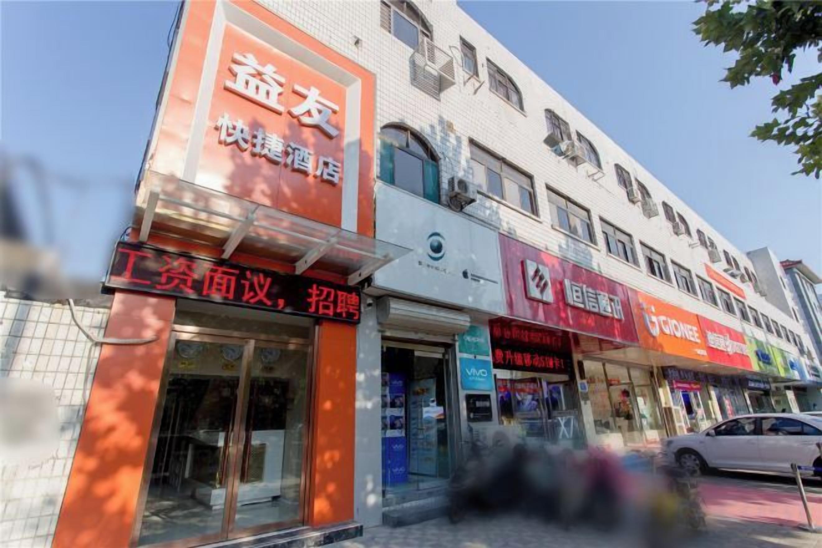 A building with multiple storefronts, including one with a sign that reads '快捷酒店'.