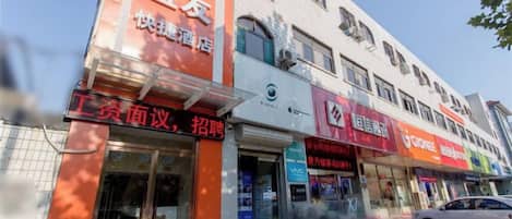 Un edificio con varias tiendas, incluyendo una con un letrero que dice '快捷酒店'.