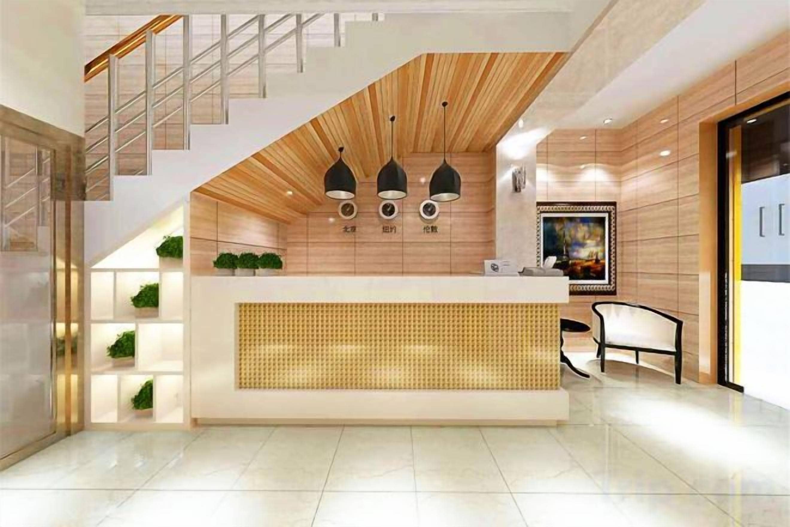 Un área de recepción moderna con un mostrador de madera, lámparas colgantes negras y una escalera que conduce a un nivel superior.