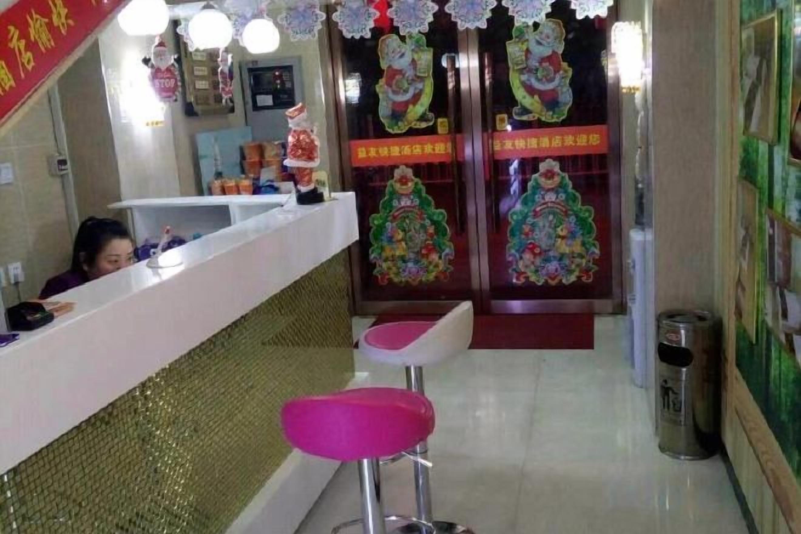 A reception area with a counter, two pink stools, and a trash can.