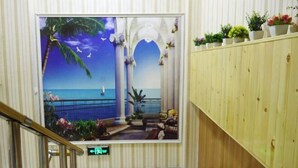 A hotel lobby with a large mural of a beach scene, a wooden reception desk, and a staircase. - Shijiazhuang Yiyou Express Hotel (Youyi South Street Hebei Province Letters and Calls Bureau Branch) (Shijiazhuang)