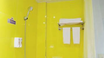 A bathroom with a yellow wall, a shower, and a towel rack with two towels.