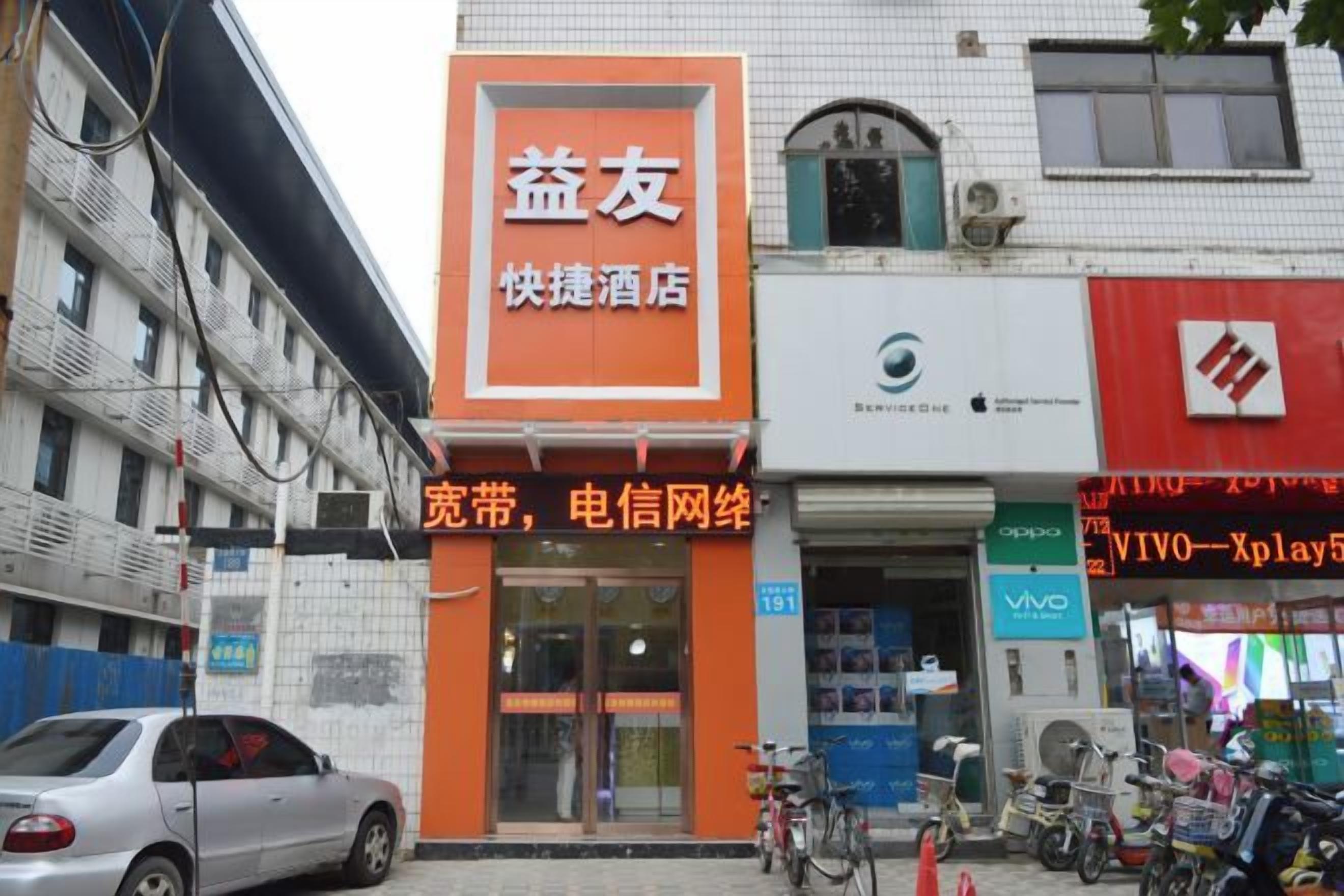 A hotel with an orange sign, a visible entrance, and a bicycle parked outside.