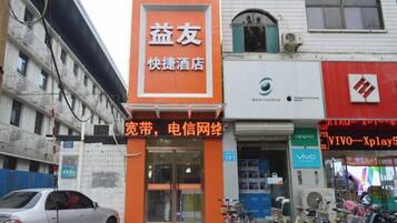 A hotel with an orange sign, a visible entrance, and a bicycle parked outside.