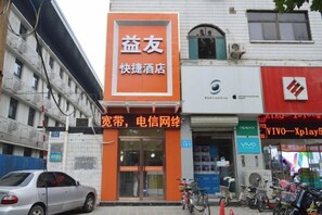 A hotel with an orange sign, a visible entrance, and a bicycle parked outside.