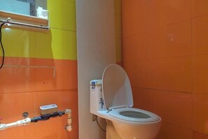 Un baño con inodoro blanco, secamanos y toallero.