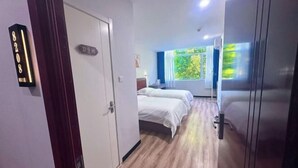 A hotel room with a wooden floor, two beds, a window with a view of greenery, and a door with a number sign. - Shijiazhuang Yiyou Express Hotel (Youyi South Street Hebei Province Letters and Calls Bureau Branch) (Shijiazhuang)