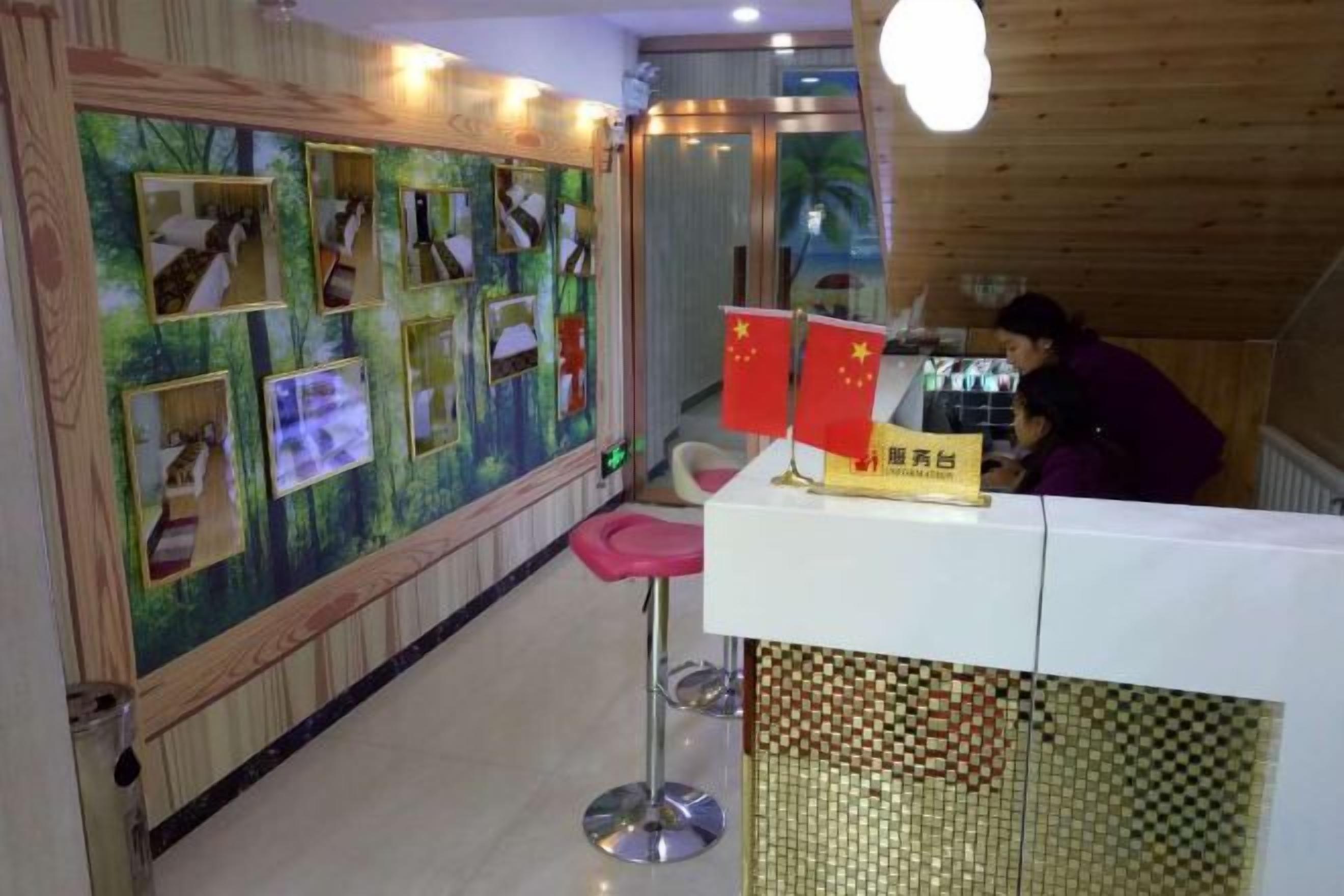 Zona de recepción con mostrador blanco, una silla roja y una pared decorada con fotografías y banderas.