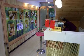 Zona de recepción con mostrador blanco, una silla roja y una pared decorada con fotografías y banderas.