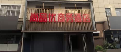 A hotel entrance with a prominent red sign and a modern facade.