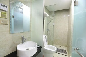 Bathroom features a glass-enclosed shower, sink, and toilet with a glass enclosure.