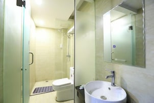 Un baño con inodoro, lavamanos y cabina de ducha de vidrio.