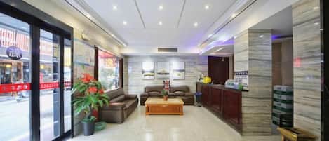 Un hall de hotel con mostrador de recepción, zona de estar y amplios ventanales.