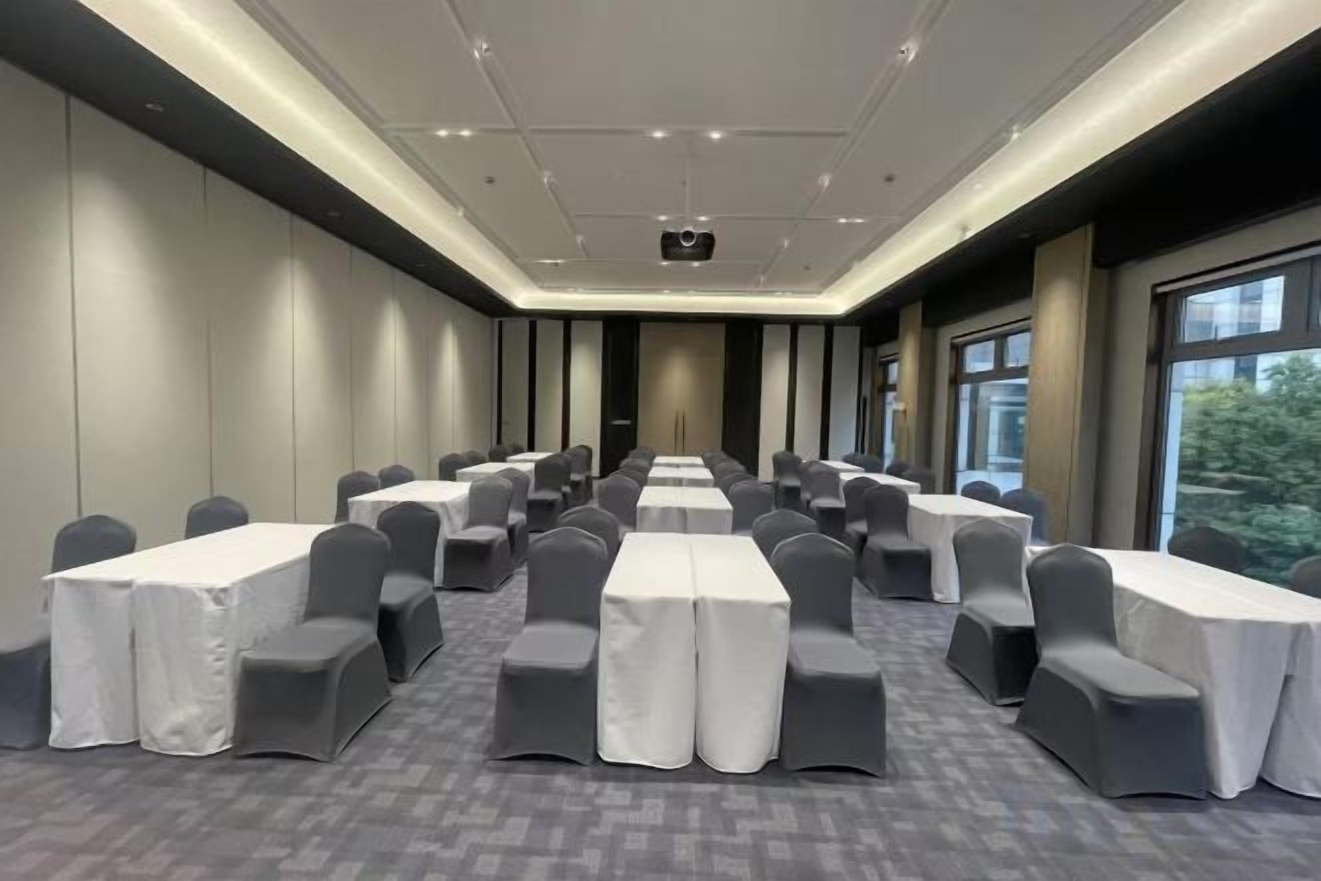 A conference room with rows of tables and chairs, a projector, and large windows.